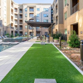 Relax and Unwind Poolside Outdoor lounge at Cadence at Frisco Station apartments in Frisco, TX, featuring astroturf and outdoor seating.